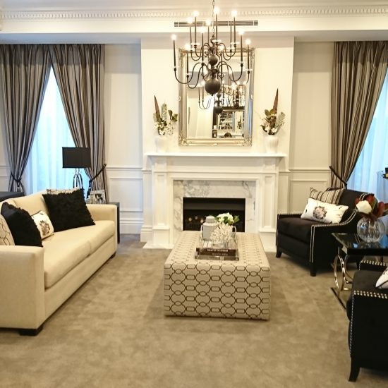 loungeroom, formal lounge, chandelier, black chandelier, tieback curtains, recessed pelmet, fireplace, marble fireplace, elegant décor, decorating, classical style, ottoman, upholstered ottoman, custom curtains, custom cushions, neutral scheme, black and white, black and white decorating, black armchairs, velvet armchairs, studded armchairs, fireplace mirror