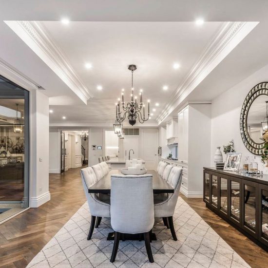 dining room, meals area, upholstered chairs, studded chairs, diamond buttoned chairs, round mirror, black chandelier, floor rug, diamond pattern rug, rug under dining table, sideboard, custom sideboard, timber floor, herringbone flooring