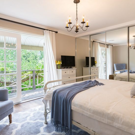 Hamptons style, Hamptons bedroom, iron bed, white iron bed, Hamptons chandelier, iron chandelier, bedroom floor rug, French doors, white curtains, sheer curtains, iron curtain rod