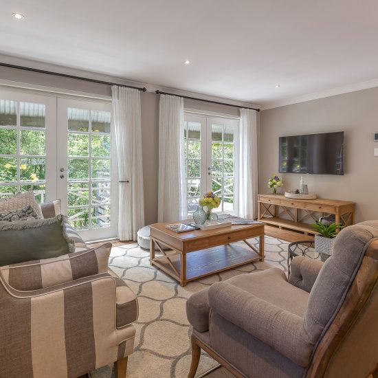 Hamptons style, Hamptons lounge room, striped sofa, timber coffee table, floor rug, diamond patterned rug, white curtains, sheer curtains, iron curtain rod, iron holdback, timber entertainment unit, French doors