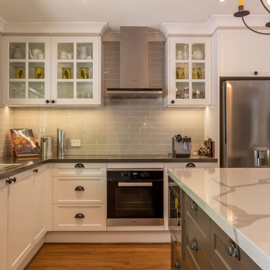 Hamptons kitchen, Hamptons style, chandelier over island, iron chandelier, shaker cabinet doors, calacutta stone benchtop, panelled glass cabinet doors, engineered timber floor, subway tiles, grey subway tiles, cup pull handles