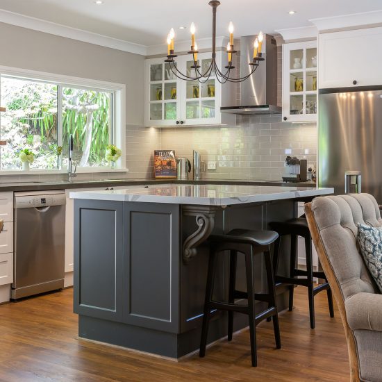 Contact us for an initial consultationHamptons kitchen, Hamptons style, chandelier over island, iron chandelier, shaker cabinet doors, calacutta stone benchtop, panelled glass cabinet doors, engineered timber floor, subway tiles, grey subway tiles